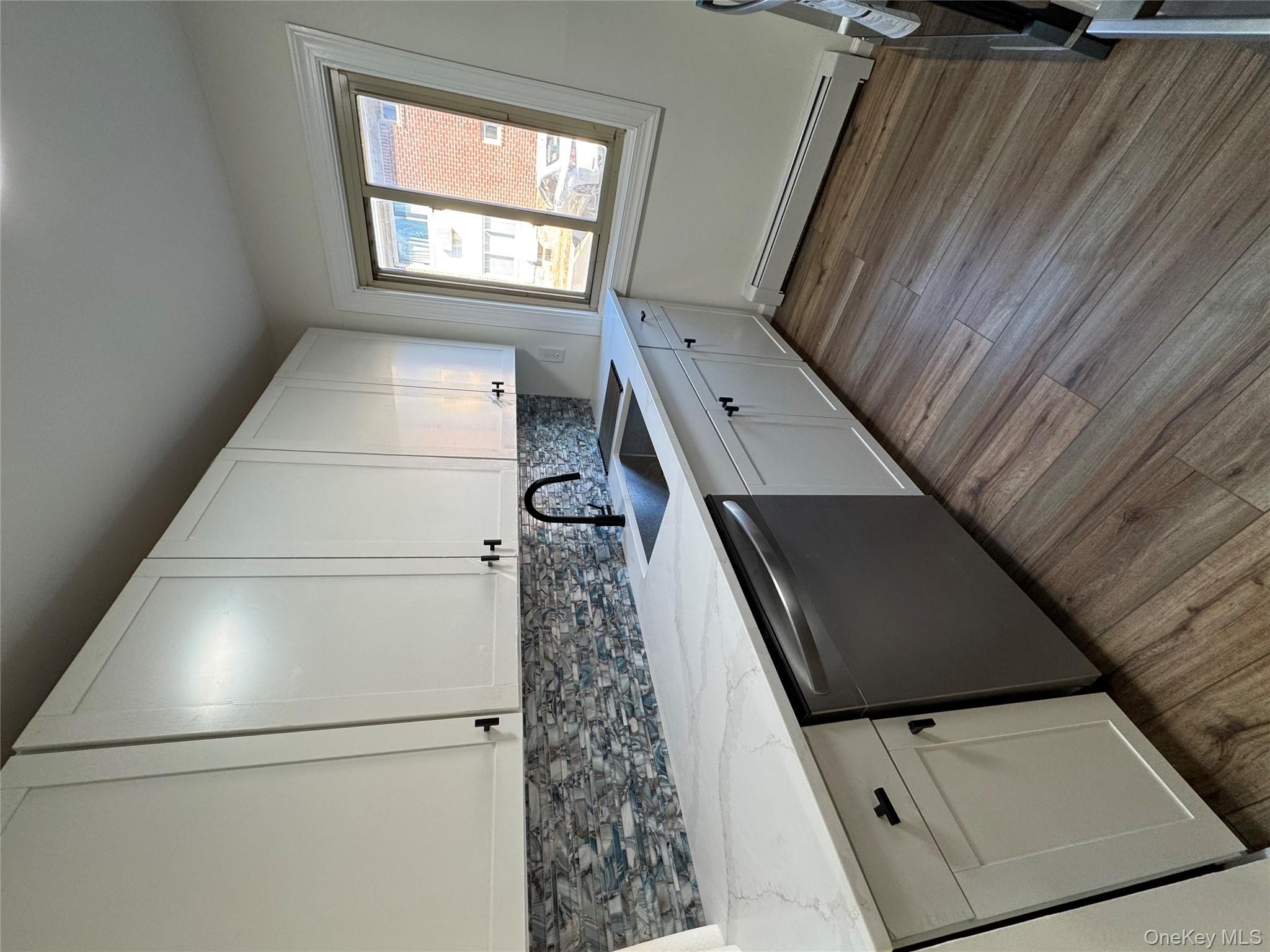 2449 I Union Avenue, Unit 34A Islip, NY 11751 - Photo 7 of 19 a kitchen with sink cabinets and wooden floor