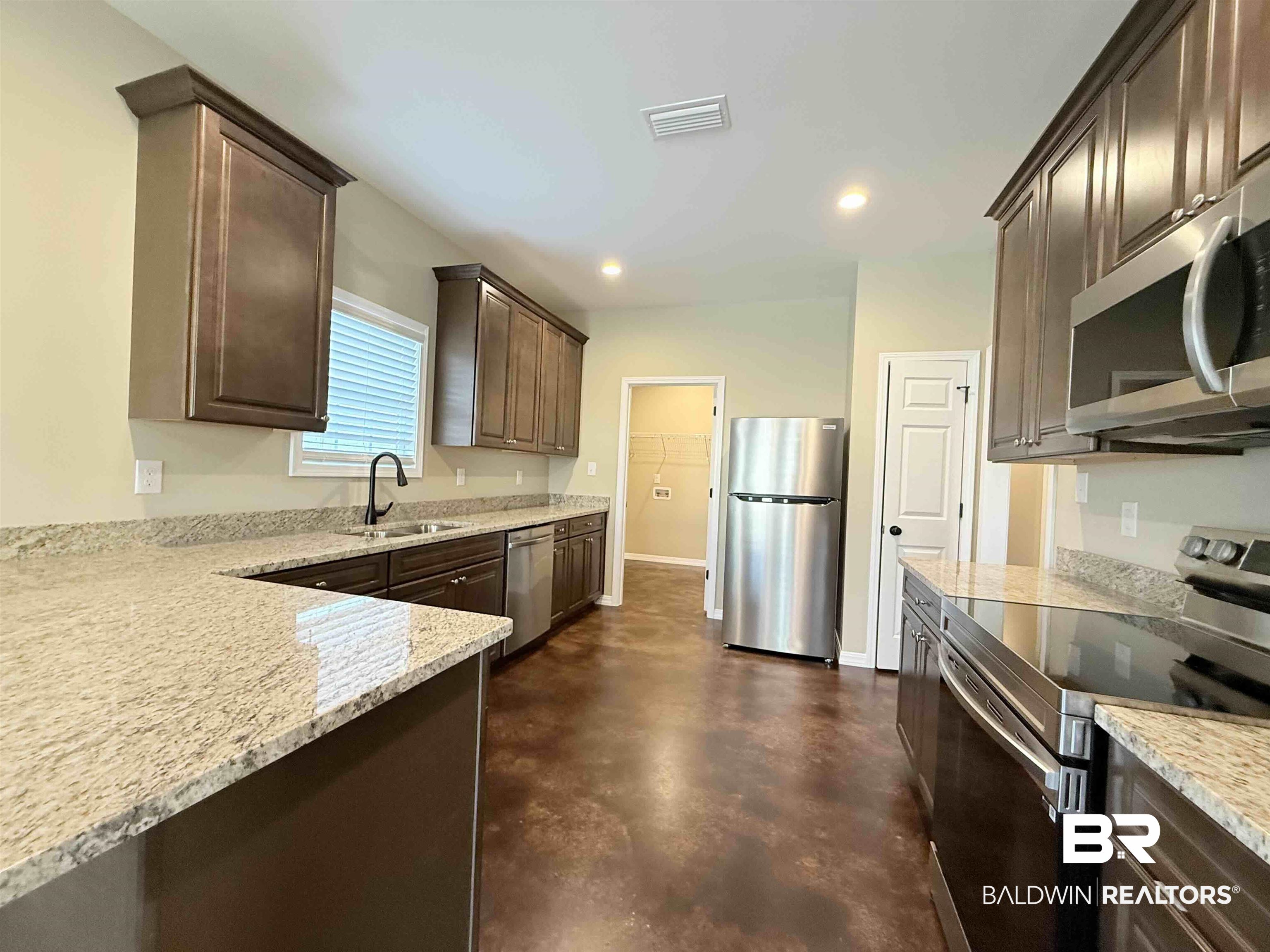 33071 -B Stables Drive, Unit B Daphne, AL 36527 - Photo 2 of 13 Kitchen with stainless steel appliances, concrete floors, light stone counters, dark brown cabinetry, and recessed lighting