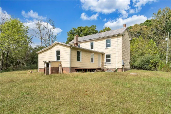 a view of a white house with a big yard and large trees