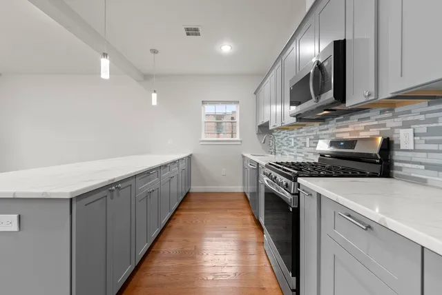 a kitchen with stainless steel appliances granite countertop a stove a sink and a microwave