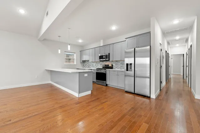 a kitchen with stainless steel appliances a refrigerator and wooden floor
