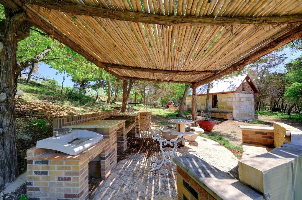 324 East Headwaters Ranch Road Kendalia, TX 78027 - Photo 55 of 61 a view of a patio with table and chairs barbeque potted plants and large tree
