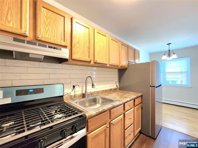 a kitchen with granite countertop a stove a sink and a refrigerator
