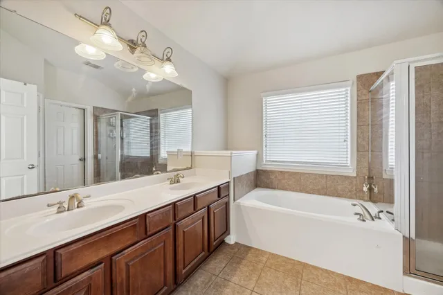 a bathroom with a tub a sink double vanity and a large mirror