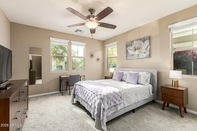a bedroom with a bed a computer on the desk and a dresser