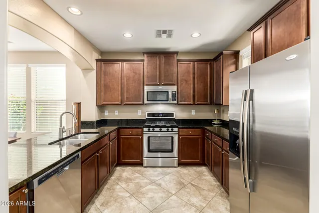 a kitchen with kitchen island granite countertop a sink stainless steel appliances and cabinets