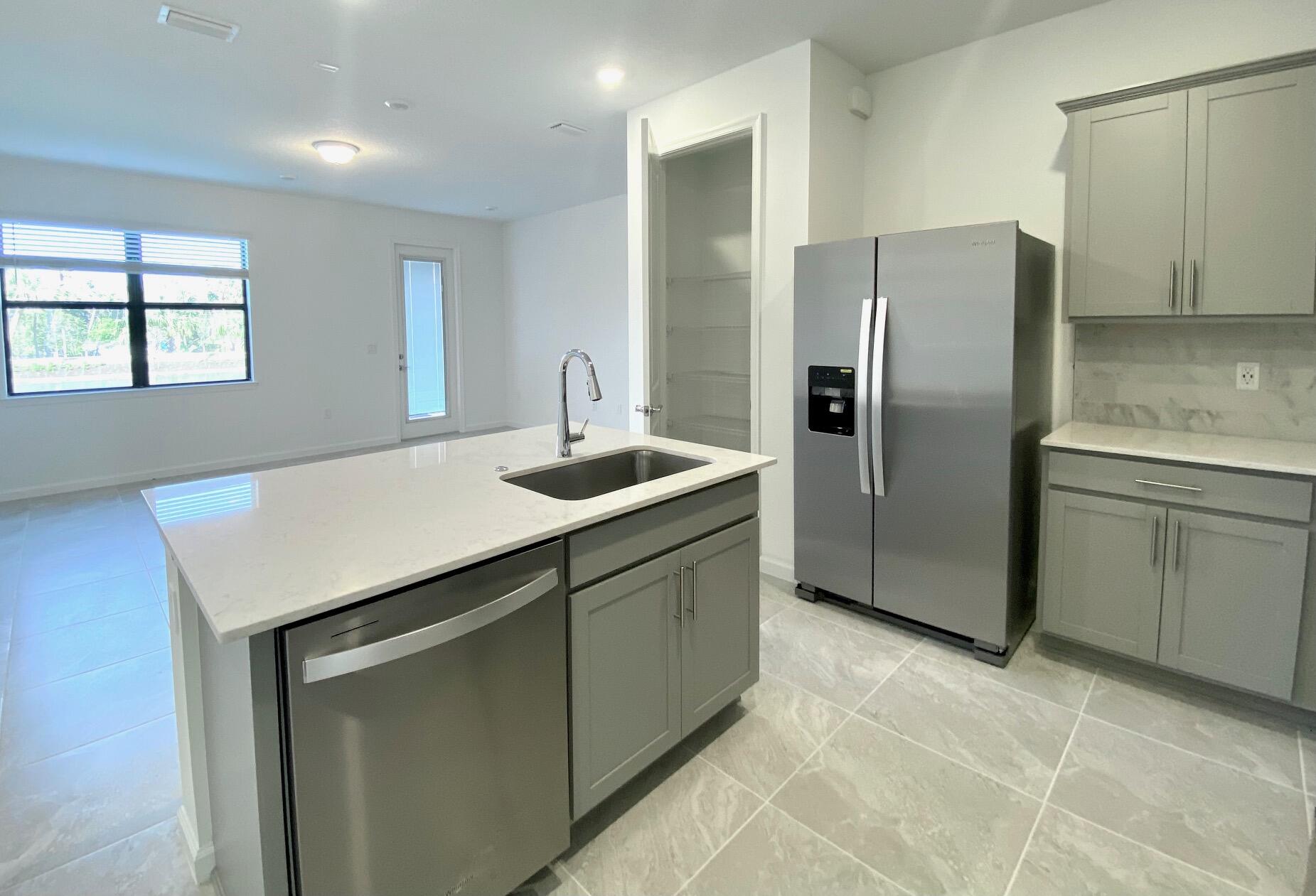 7594 Southwest Linus Lane, Unit LATITUDE 902 Stuart, FL 34997 - Photo 9 of 21 a kitchen with stainless steel appliances granite countertop a sink stove and refrigerator