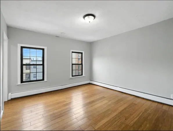 a view of an empty room with wooden floor and window