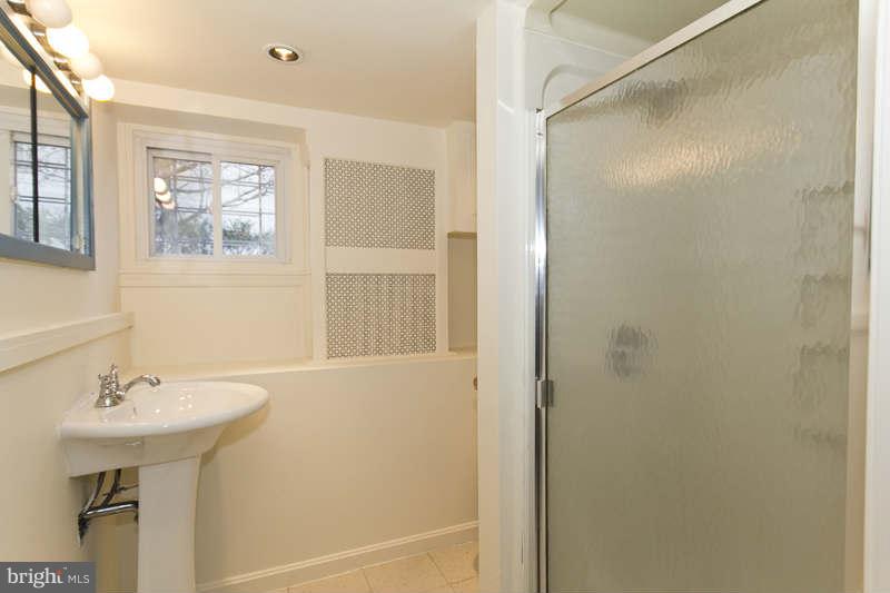 509 Kingston Road Baltimore, MD 21229 - Photo 11 of 17 a bathroom with a sink a mirror a window and a shower
