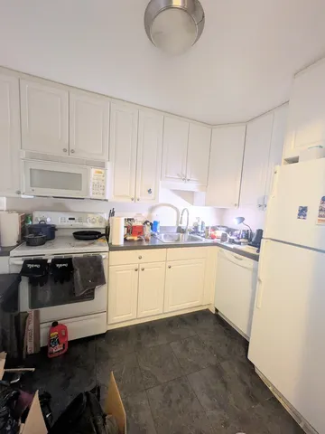 a kitchen with granite countertop white cabinets and white appliances