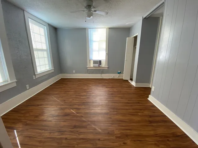 an empty room with wooden floor and windows