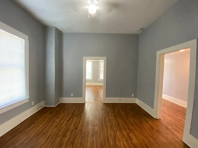 an empty room with wooden floor and windows