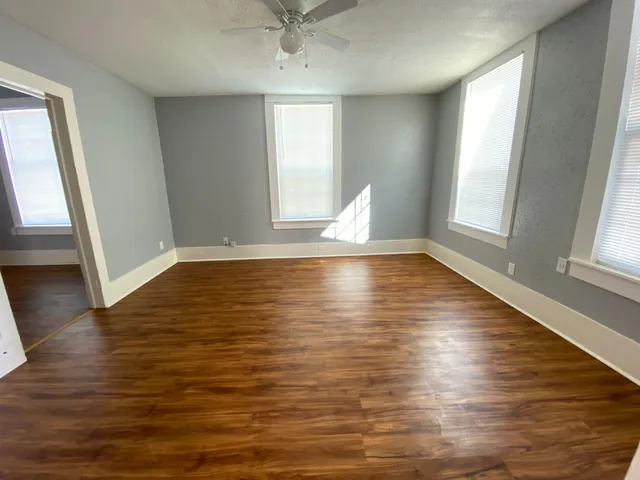 a view of empty room with wooden floor and fan