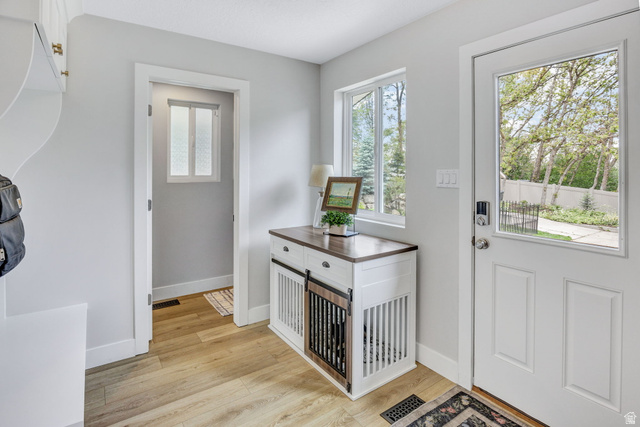 1350 Canyon Park Road Bountiful, UT 84010 - Photo 28 of 38 Entryway featuring a white paneled door with a glass insert, wood-finish flooring, light grey walls, and a built-in white storage bench with brass hardware