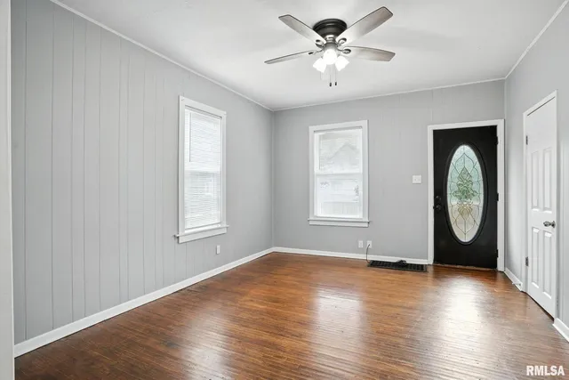 an empty room with wooden floor fan and windows