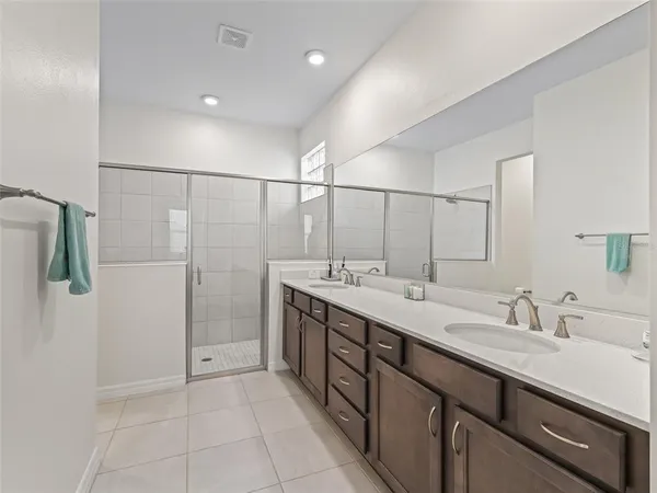 a spacious bathroom with a double vanity sink a mirror and shower