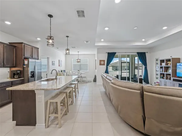 a large kitchen with kitchen island a large counter top space a sink a refrigerator a stove a chimney a couches and a bookshelf