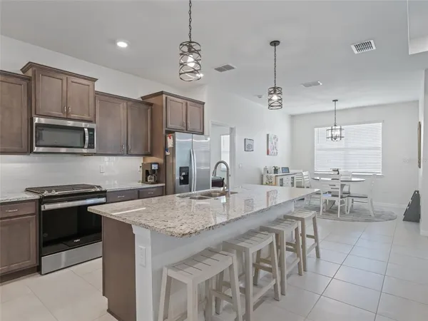 a large kitchen with granite countertop a stove a sink a microwave and a dining table