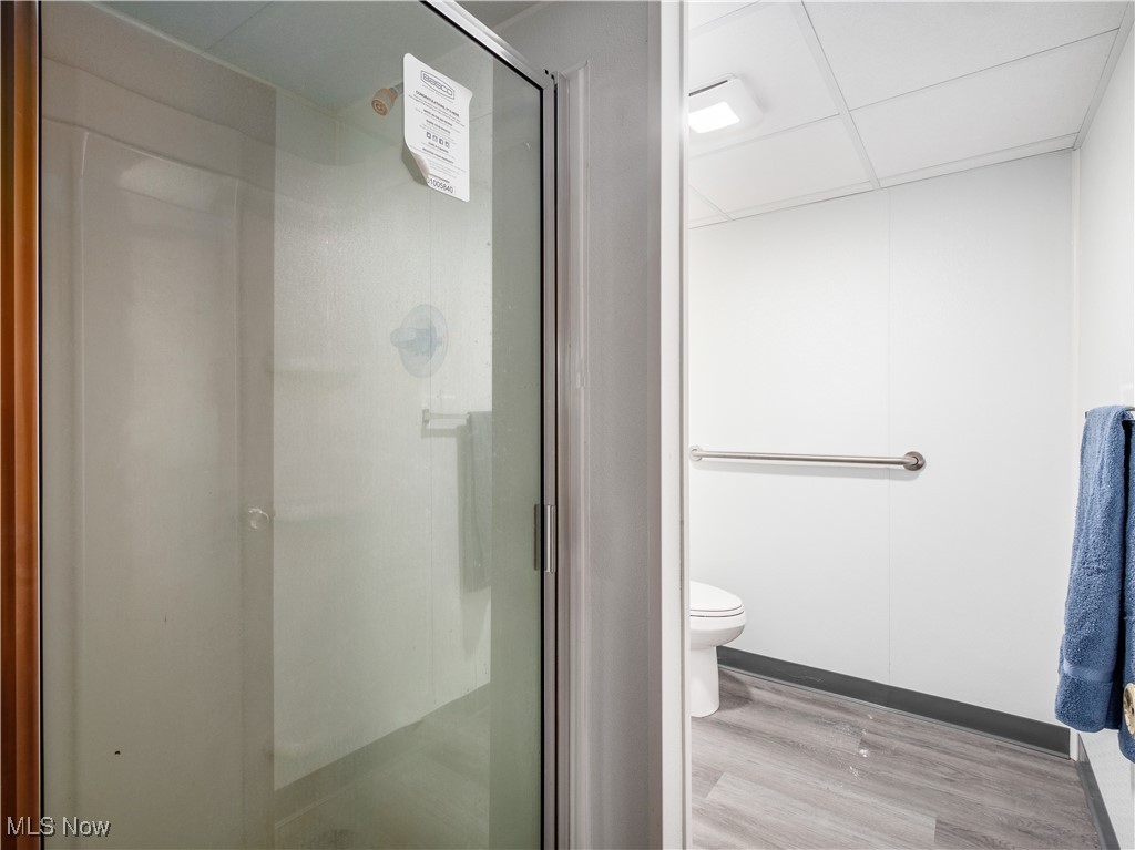 12454 Old Rainer Road Roseville, OH 43777 - Photo 25 of 33 Bathroom with wood-type flooring, toilet, a shower with door, and a drop ceiling