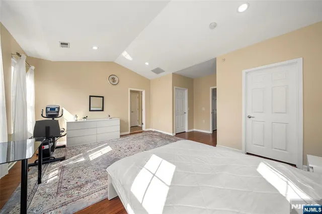 a spacious bedroom with a large bed a chandelier and closet