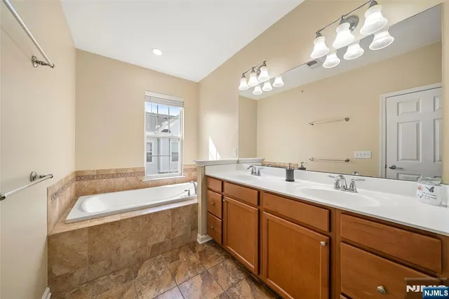 a spacious bathroom with a double vanity sink a large mirror and a bathtub