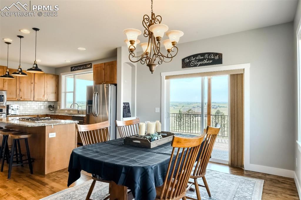 34698 Southern Cross Loop Kiowa, CO 80117 - Photo 14 of 50 a dining room with wooden floor a chandelier a wooden table and chairs