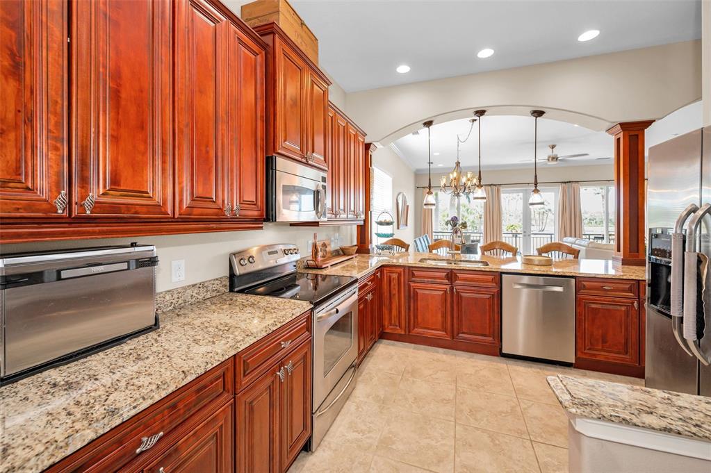 47 West Morgan Street Tarpon Springs, FL 34689 - Photo 30 of 64 a large kitchen with stainless steel appliances granite countertop a stove a sink dishwasher and a refrigerator with wooden cabinets