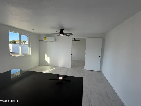 an empty room with a window and a fan