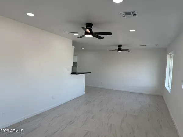 an empty room with windows and fan