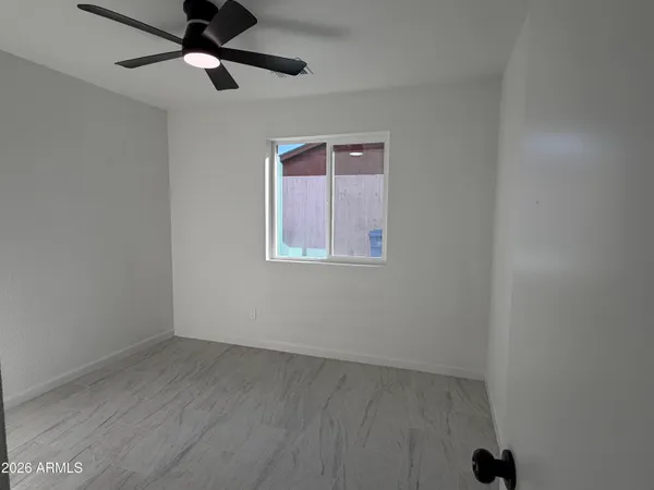 an empty room with a window and a ceiling fan
