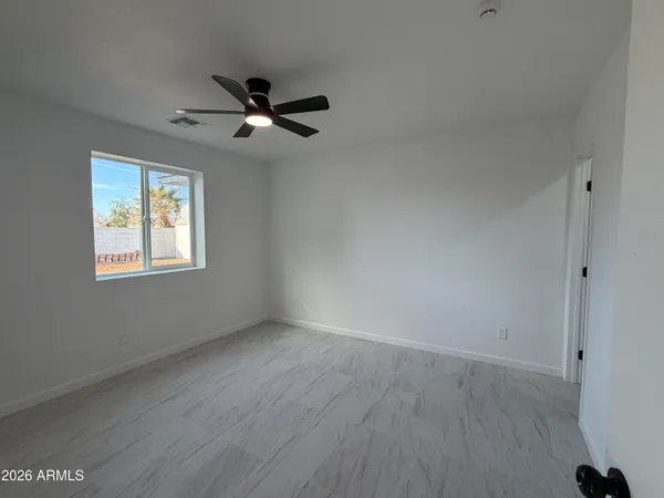 an empty room with wooden floor ceiling fan and windows