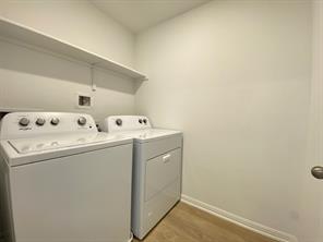 213 Saide Street Georgetown, TX 78626 - Photo 29 of 32 Dedicated laundry space featuring a white top-load washer and dryer set, a high wall-mounted shelf, light-toned wood-finish flooring, and crisp white walls