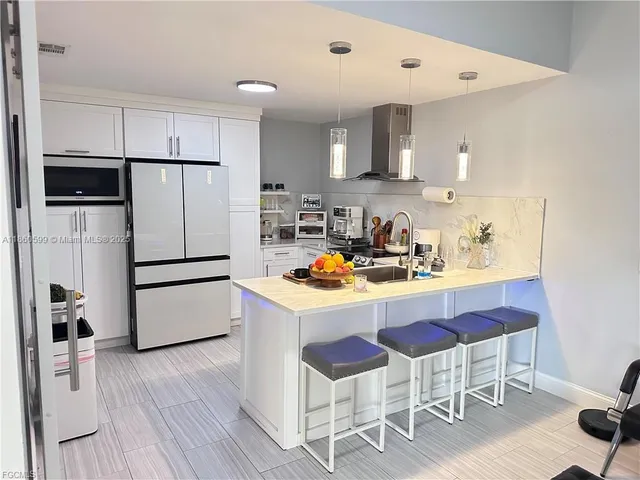 a kitchen with a refrigerator a stove a sink and a chairs