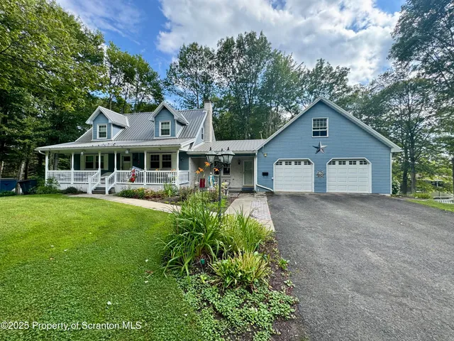 a view of a white house with a big yard and large trees