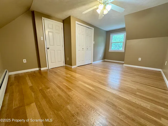 a view of an empty room with window and wooden floor