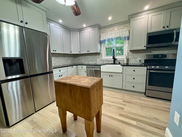 a kitchen with stainless steel appliances granite countertop a refrigerator a stove a sink dishwasher and a refrigerator with wooden floor