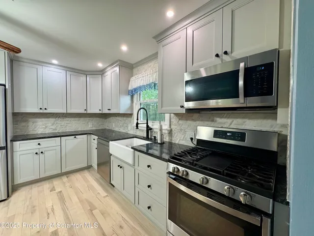 a kitchen with stainless steel appliances a stove a sink and a microwave