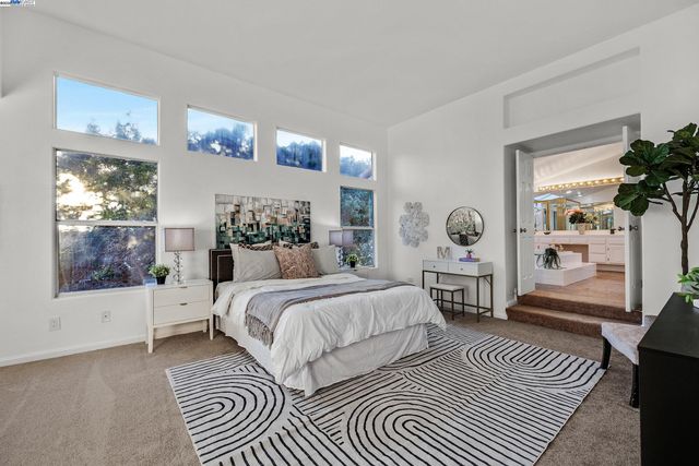 a spacious bedroom with a large bed a chandelier and windows