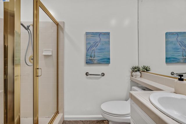 a bathroom with a granite countertop toilet a sink and a mirror