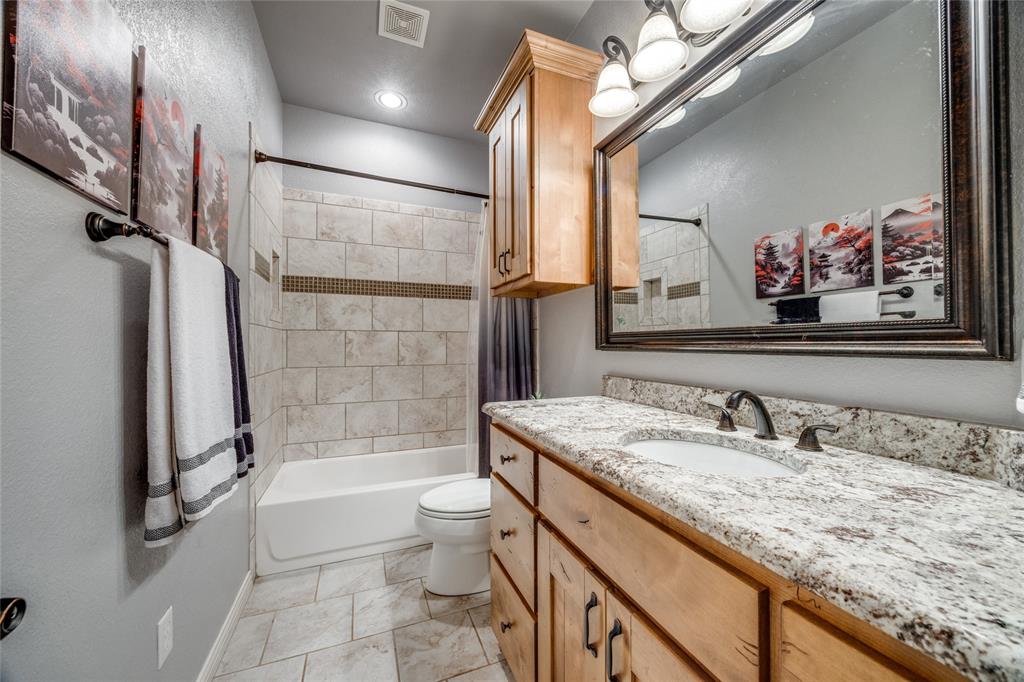 1462 Durham Road Whitewright, TX 75491 - Photo 24 of 40 a bathroom with a granite countertop sink a large mirror a bathtub and shower