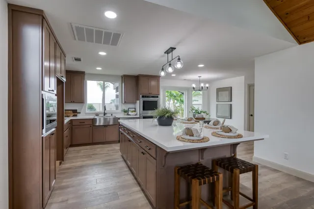 a kitchen with kitchen island granite countertop a sink and refrigerator