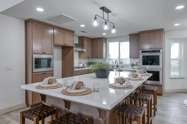 a kitchen with stainless steel appliances kitchen island granite countertop a kitchen island a stove a table and chairs