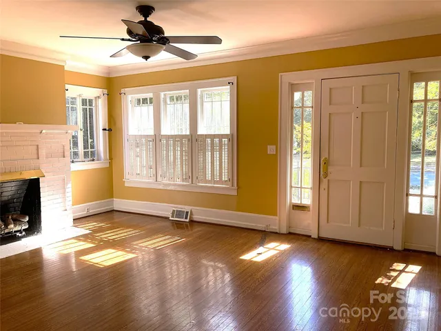 a view of an empty room with window and wooden floor