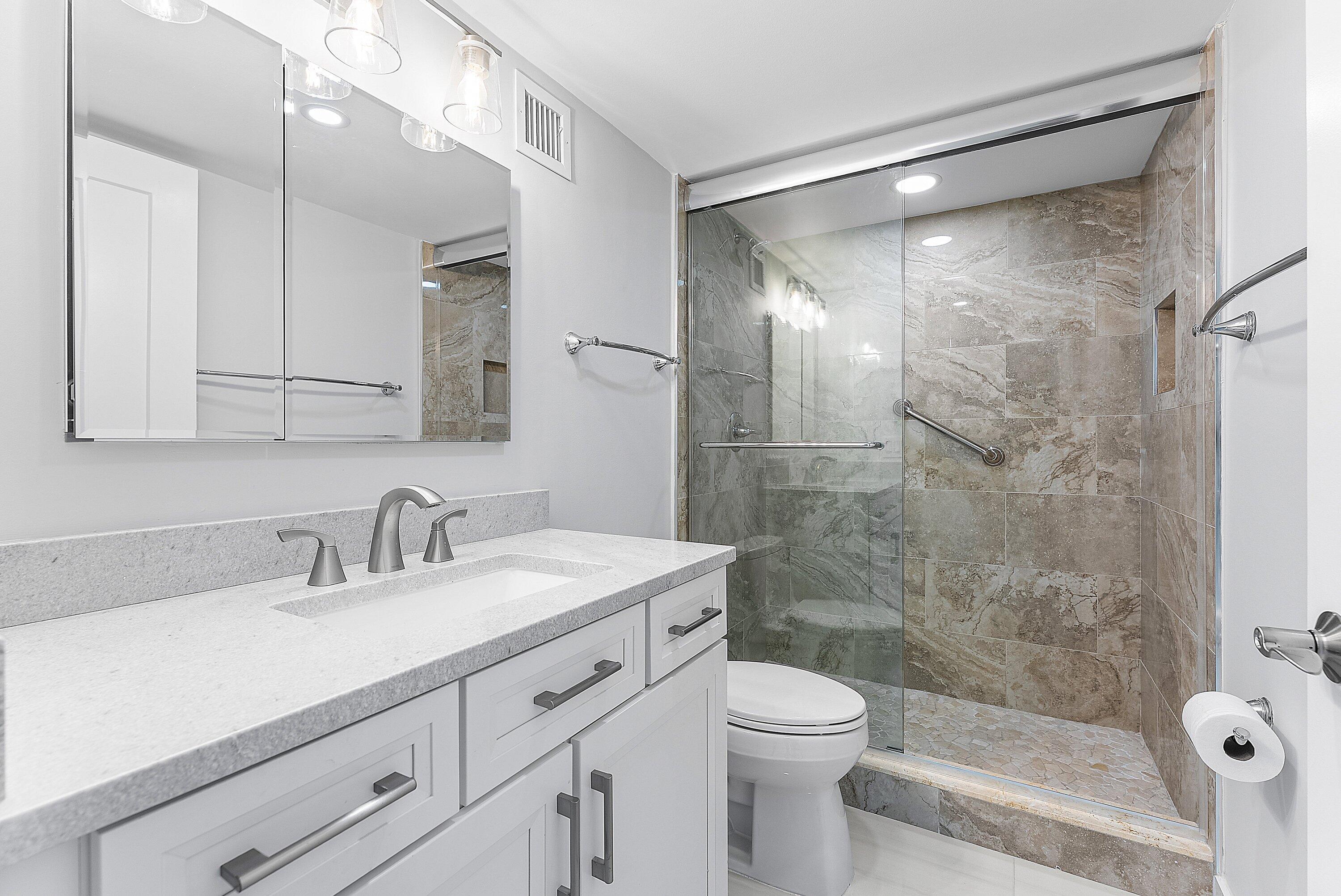 2800 South Ocean Boulevard, Unit 4E Boca Raton, FL 33432 - Photo 31 of 51 a bathroom with a shower sink vanity mirror and toilet