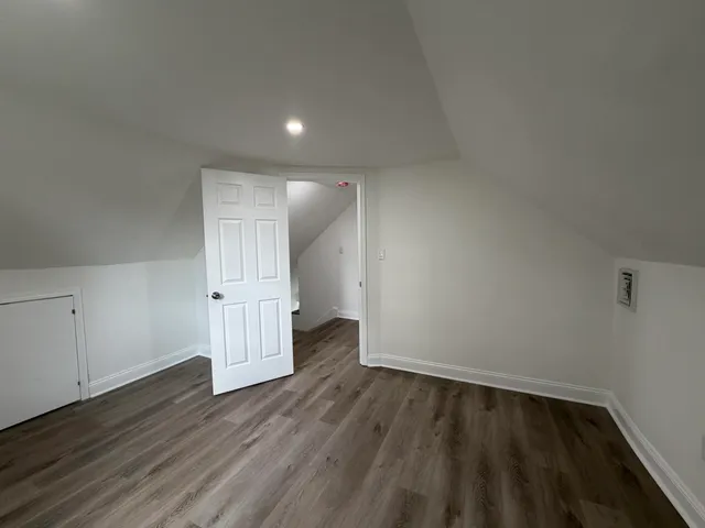a view of an empty room with wooden floor and closet
