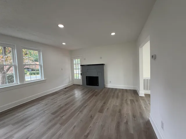 an empty room with windows and fireplace
