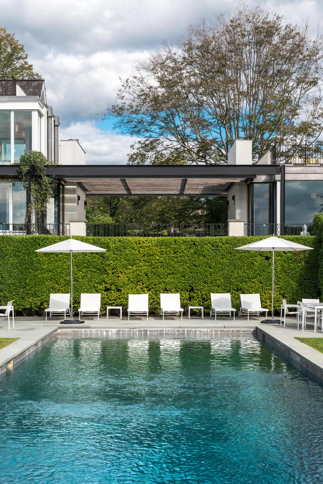 163 Pear Tree Point Road Darien, CT 06820 - Photo 4 of 24 a view of a lake with a bench and lawn chairs under an umbrella