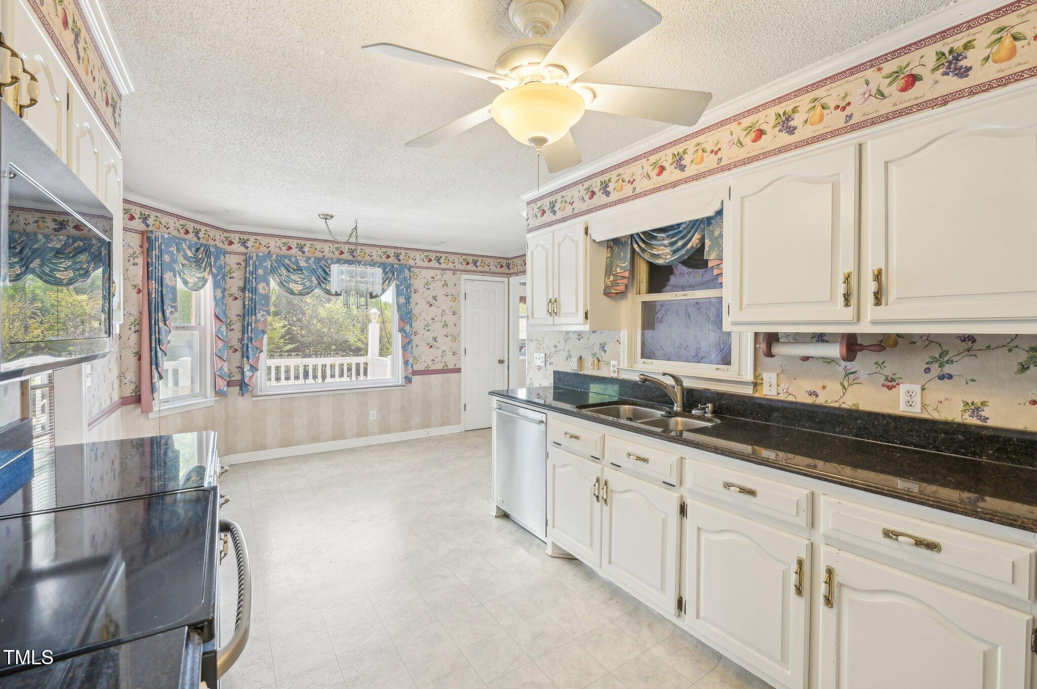 3011 Old Hillsborough Road Mebane, NC 27302 - Photo 9 of 29 a kitchen with granite countertop a stove a sink and white cabinets with wooden floors
