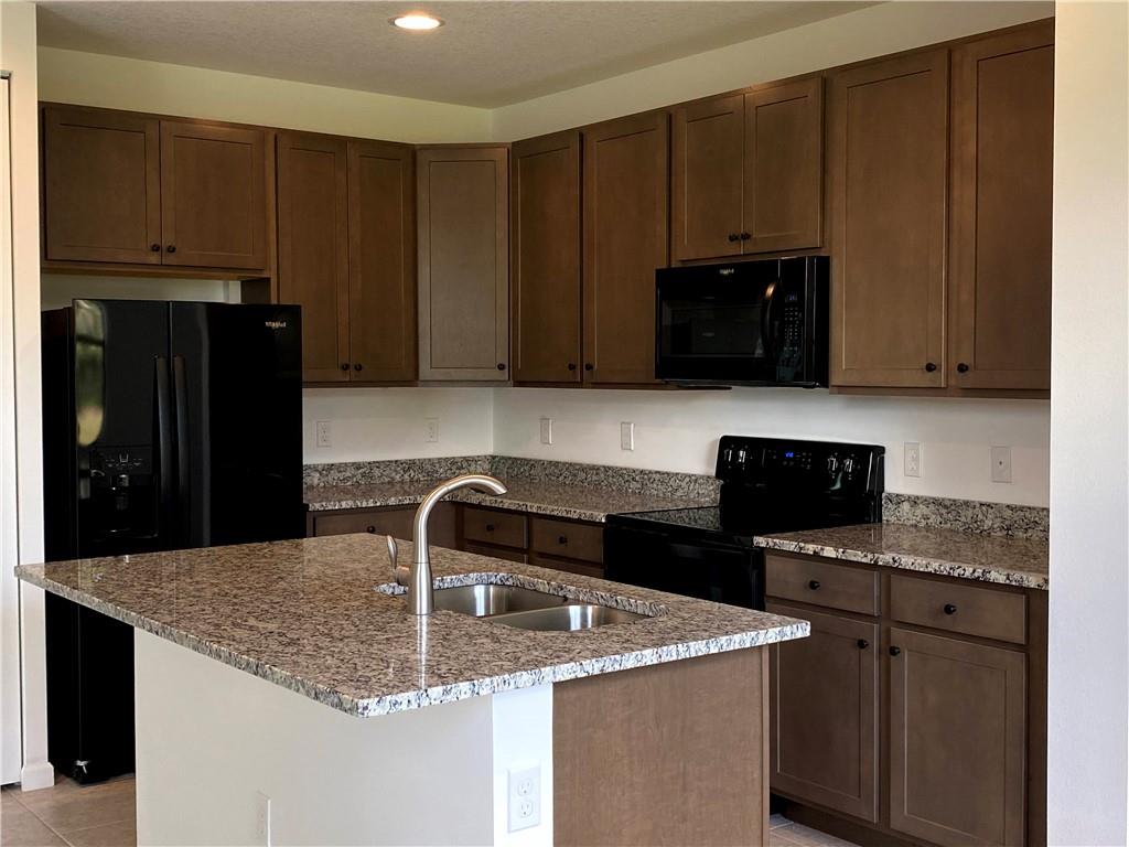 445 Northwest 33rd Lane Pompano Beach, FL 33069 - Photo 13 of 19 a kitchen with granite countertop a stove a microwave a sink and cabinets