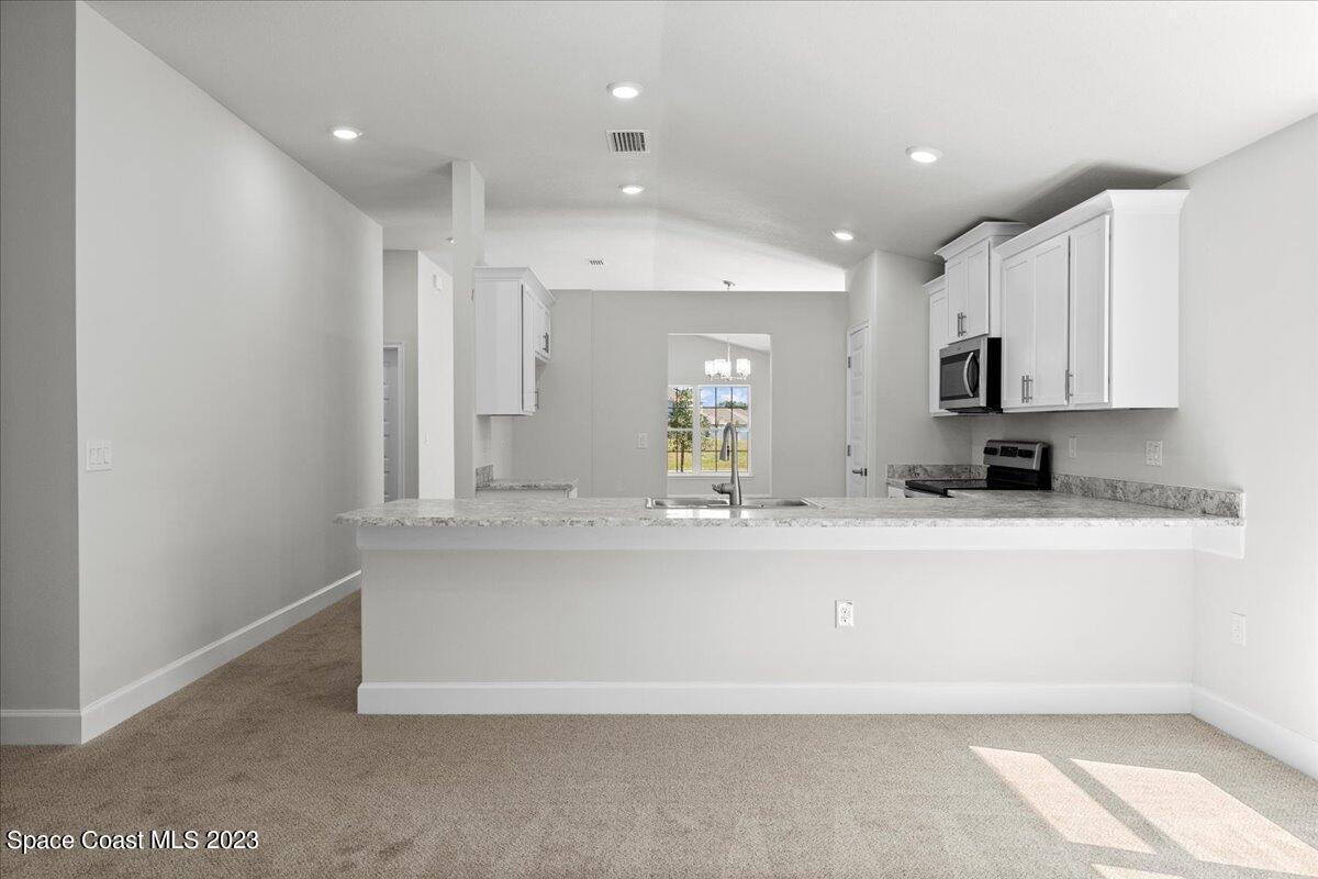 1341 Tupelo Circle Cocoa, FL 32926 - Photo 12 of 27 a large white kitchen with kitchen island a sink a stove and white cabinets